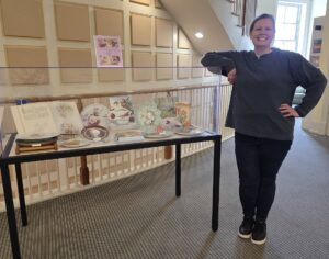Smiling artist standing next to exhibit case.